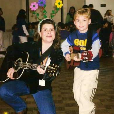 HaMo'Robyn Solovei wearing flower headband playing guitar with a young boy