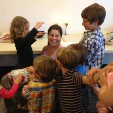 HaMo Robyn Solovei smiling surrounded by a group of happy children
