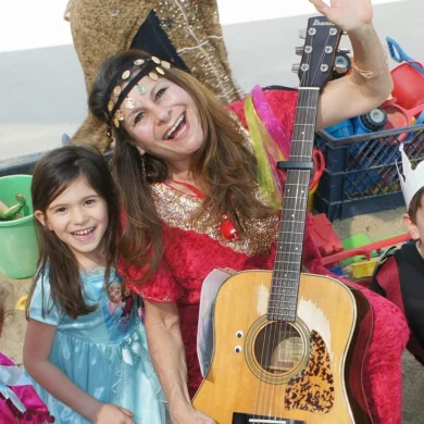 Robyn Solovei playing guitar with a young girl during a music performance
