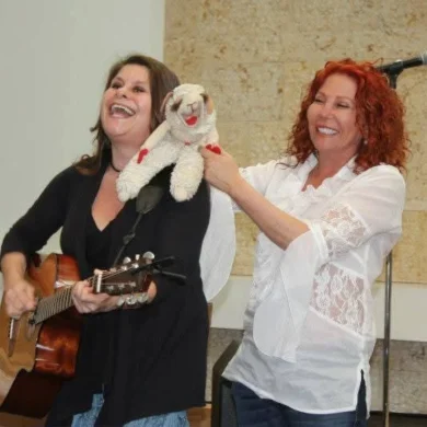 HaMo’Robyn Solovei playing guitar and performing with a puppet alongside a singer
